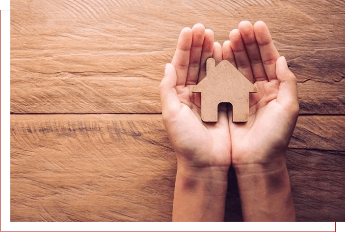 A person holding up two hands with a wooden puzzle piece in the middle.